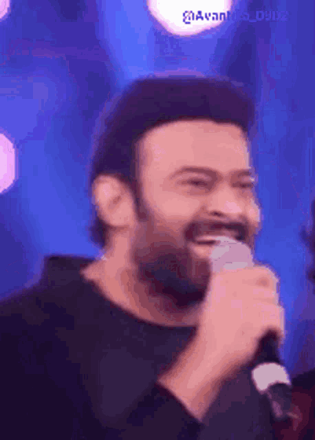 a man is singing into a microphone and smiling .