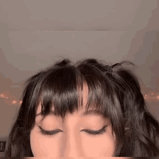 a close up of a woman 's face with her eyes closed and her hair in pigtails