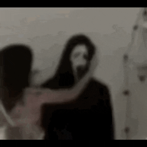 a blurry picture of a woman holding a ghost with a mask on his face .