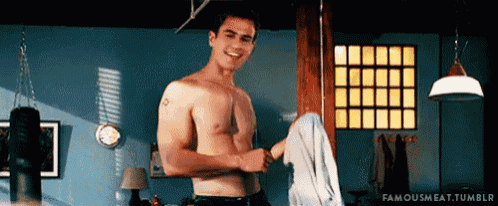a shirtless man is standing in a room and holding a towel .