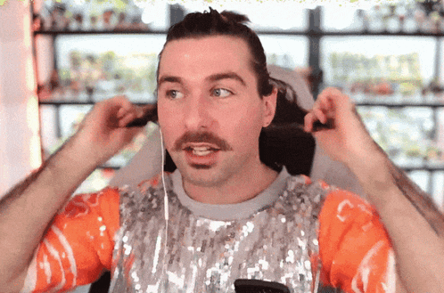 a man with a mustache is putting on ear buds