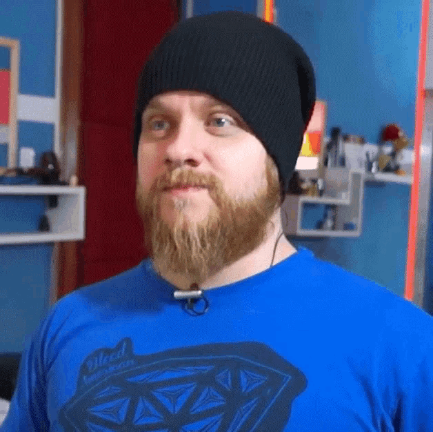 a man with a beard wearing a black hat and a blue shirt