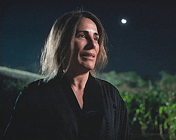 a woman in a black robe is laughing with a full moon in the background