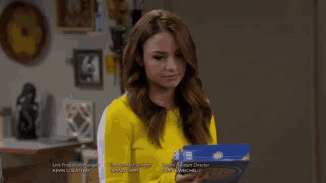 a woman in a yellow top is holding a box of ritz crackers