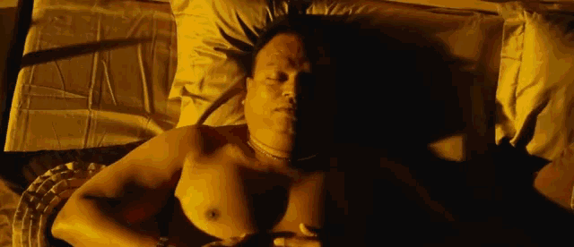 a shirtless man is laying on a bed with a pillow