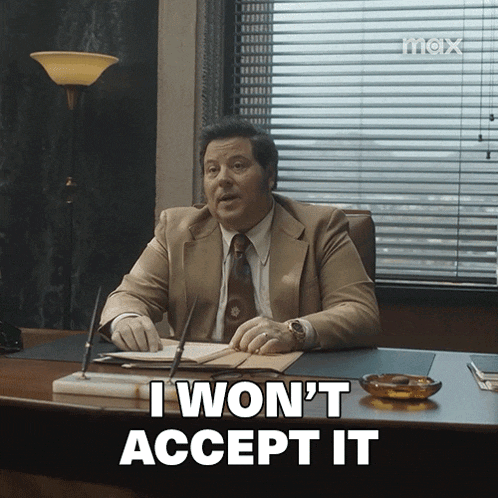 a man in a suit and tie is sitting at a desk and says i won 't accept it
