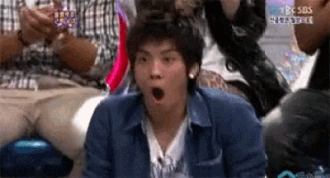 a man with a surprised look on his face is sitting in front of a group of people with sbs written on the bottom