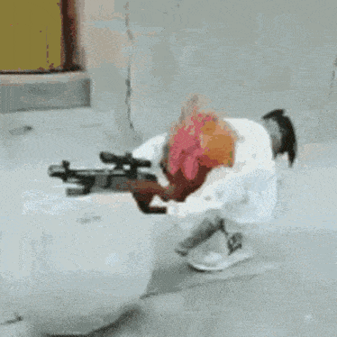 a person is kneeling down with a gun in their hands .