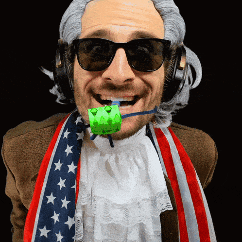 a man wearing a wig and sunglasses has a green object in his mouth that says ' a ' on it