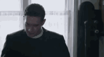 a man in a suit and tie is standing in front of a window in a room .