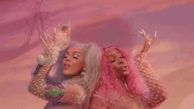 two women with pink hair are standing next to each other .