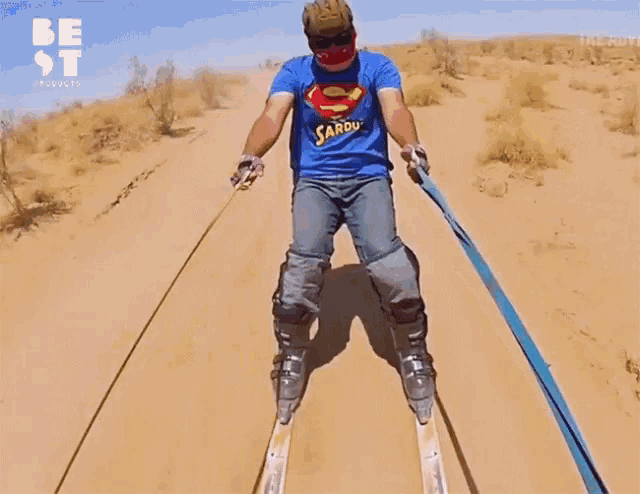 a man wearing a superman shirt is skiing down a sand dune
