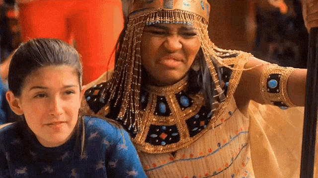 a woman in a costume is standing next to a girl in a blue shirt .
