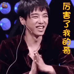 a man with a microphone on his ear is smiling and holding his hands together