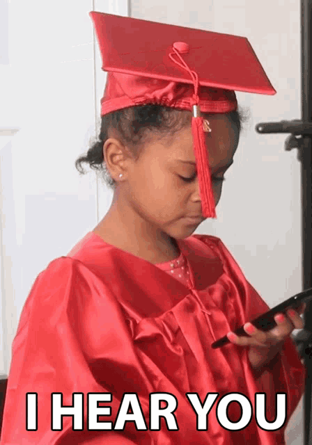 a little girl wearing a graduation cap and gown looks at her cell phone with the caption i hear you