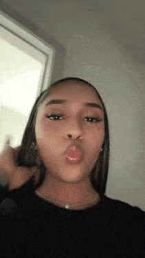 the girl is wearing a black shirt and a necklace and is making a kissing face .