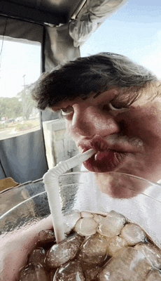 a man drinking through a straw from a glass