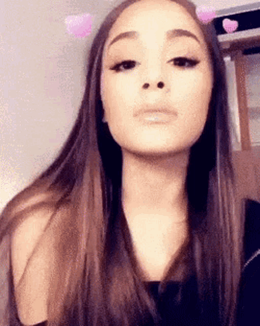 ariana grande is wearing a snapchat filter with hearts on her ears .