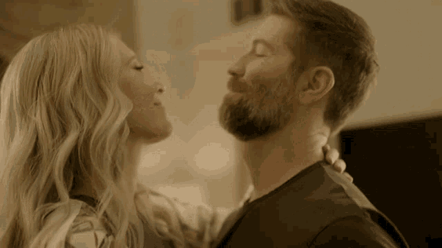 a man with a beard is kissing a woman
