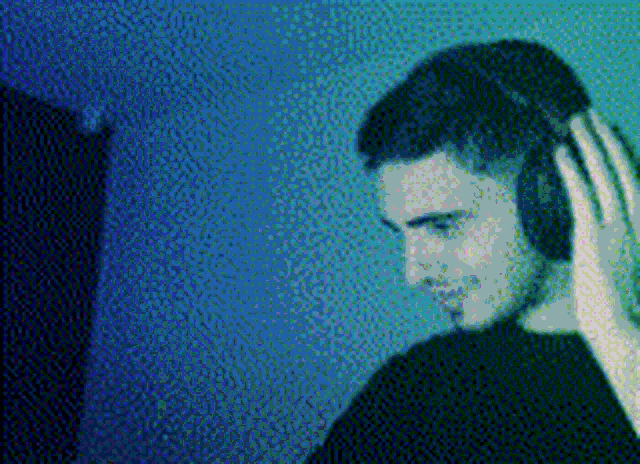 a man wearing headphones in a dark room with a blue background