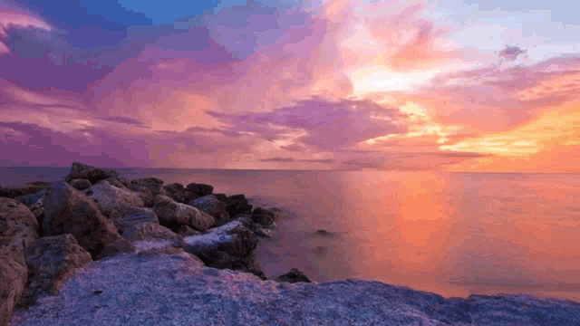 a sunset over the ocean with purple and orange clouds