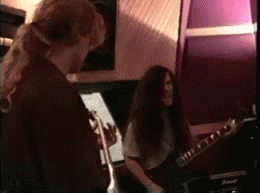 a man with long hair is playing a guitar