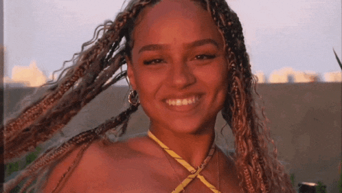 a woman with braids and a yellow top is smiling