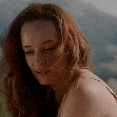 a close up of a woman 's face with mountains in the background