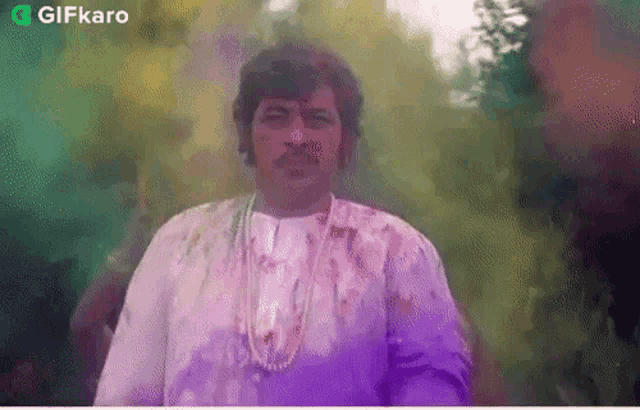 a man in a purple shirt is standing in front of a purple background .