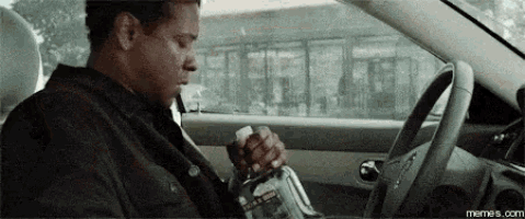 a man is sitting in a car holding a bottle of water in his hand .
