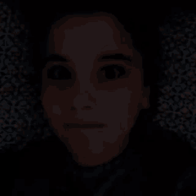 a close up of a person 's face in the dark with their eyes closed .