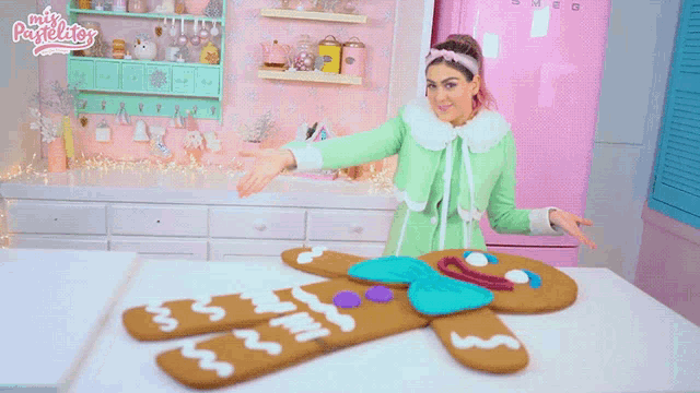 a woman is standing next to a large gingerbread man on a table in front of a sign that says mis pastelitos