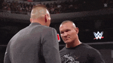 two wrestlers are standing next to each other in a wrestling ring .