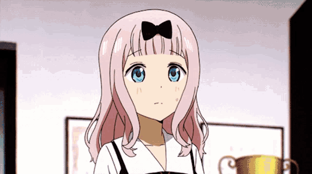 a girl with pink hair and blue eyes has a bow in her hair .