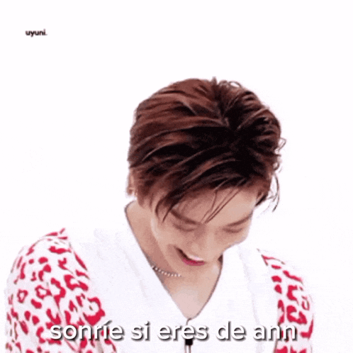 a young man is smiling with the words sonrie si eres de ann behind him .