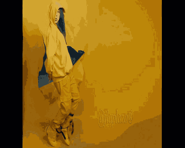 a woman in a yellow hoodie and yellow pants stands in front of a yellow wall