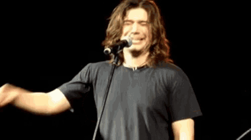 a man with long hair is singing into a microphone