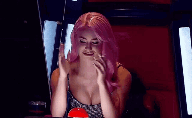a woman with pink hair and a very plunging neckline is clapping her hands