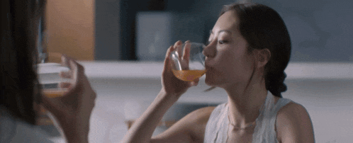a woman drinking a glass of orange juice from a glass