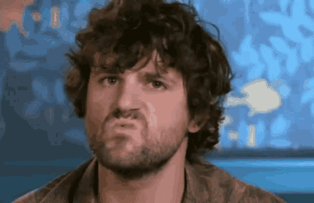 a man with curly hair and a beard makes a funny face