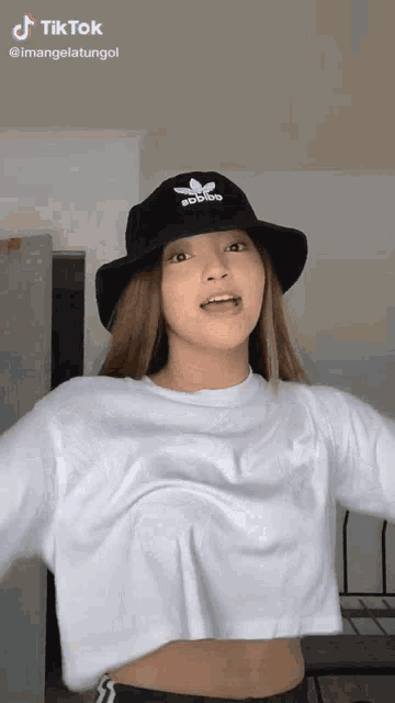 a woman wearing a black hat and a white crop top