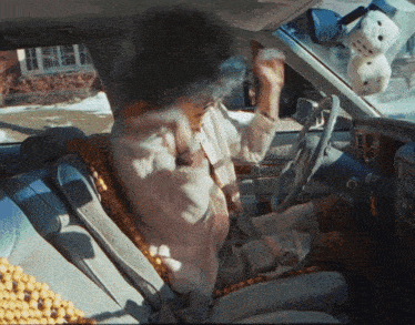 a woman is sitting in a car with a hello kitty stuffed animal on the dashboard