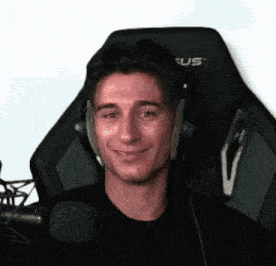 a man wearing headphones and a black shirt is sitting in a chair in front of a microphone .