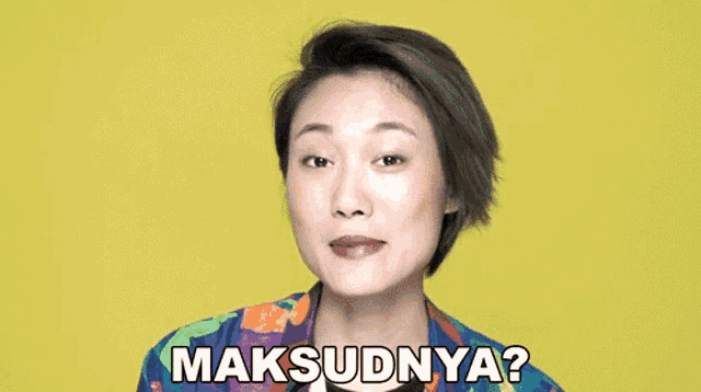 a woman in a colorful shirt says " maksudnya " in front of a yellow background