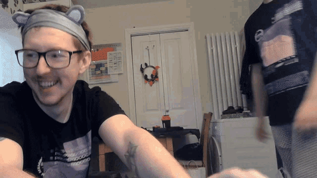 a man wearing glasses and a headband with cat ears is smiling