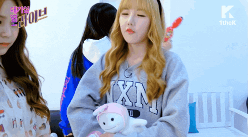 a girl holding a stuffed animal wearing a sweater that says ixn on it