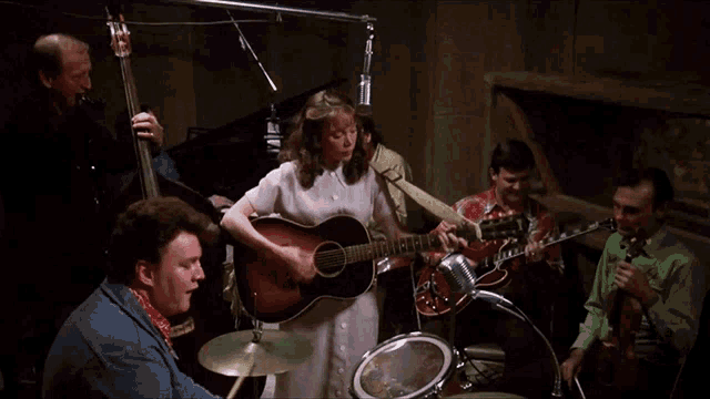 a woman plays a guitar in a band with other musicians