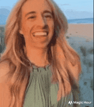 a woman in a green dress is taking a selfie on the beach .