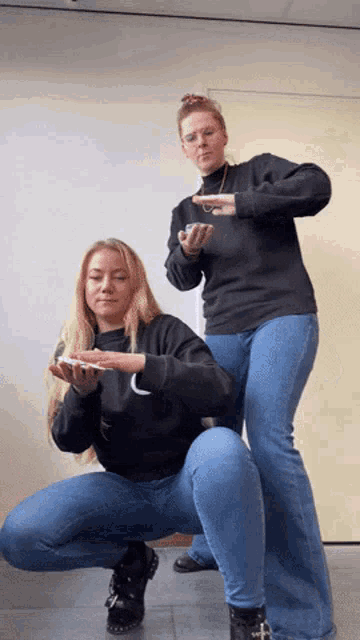 a woman squatting next to another woman who is wearing a black nike shirt