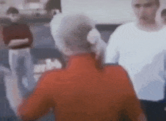 a blurry picture of a man in a red shirt standing next to a woman in a white shirt .